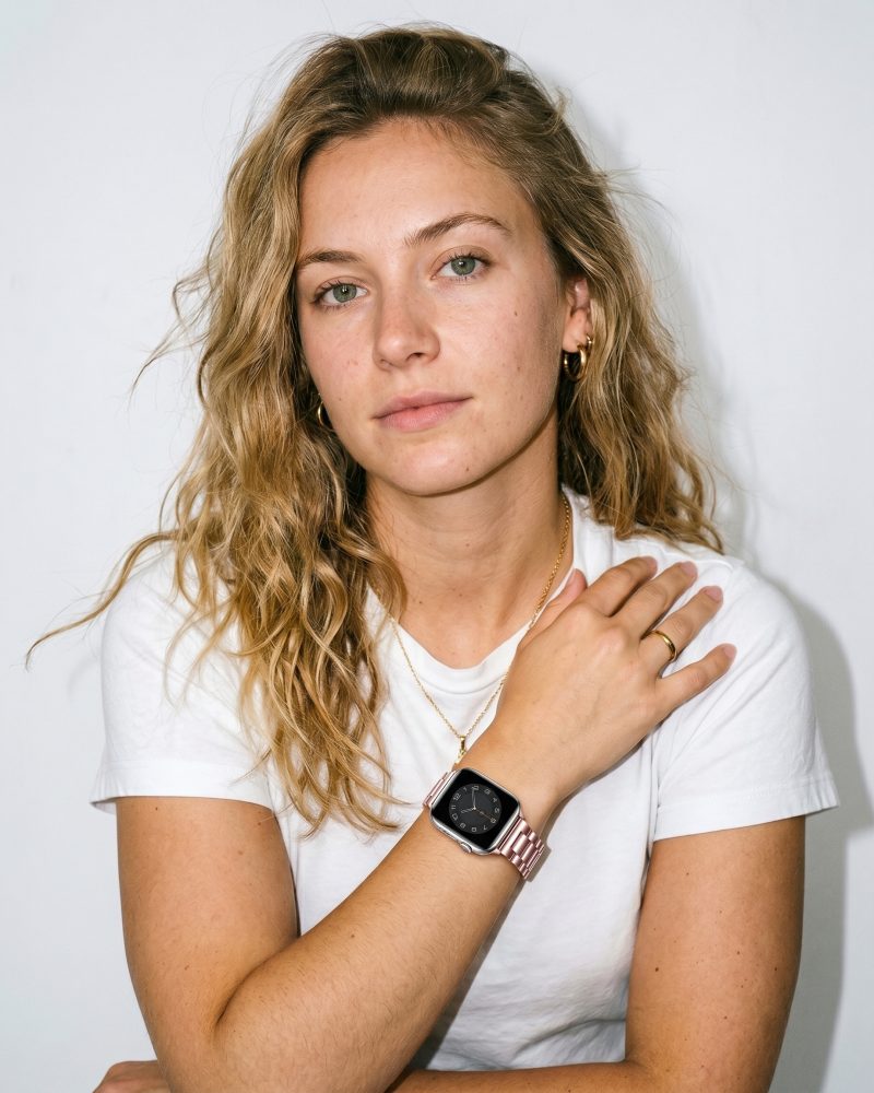 Woman wearing rose gold steel strap smartwatch with white t-shirt