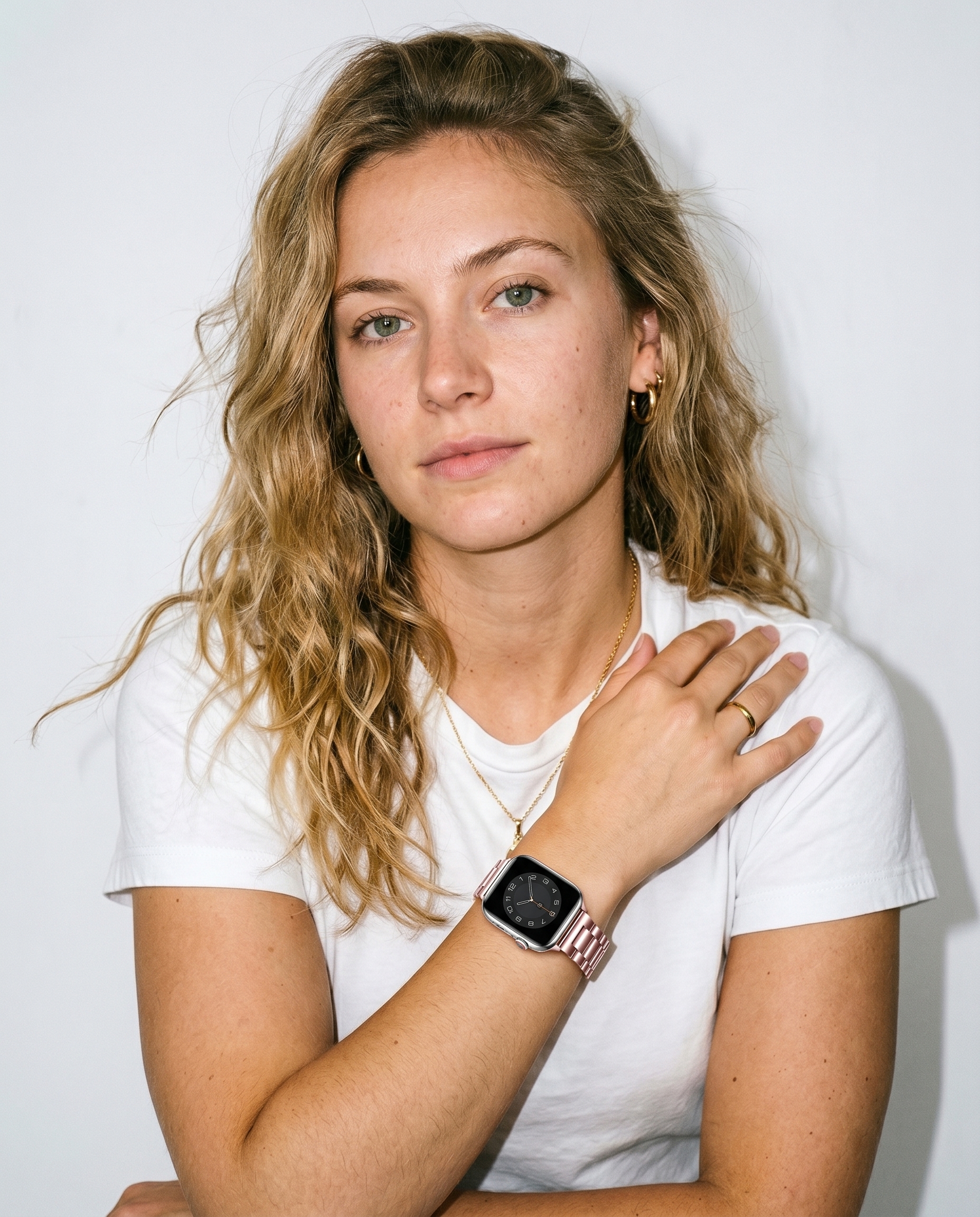 Woman wearing rose gold steel strap smartwatch with white t-shirt