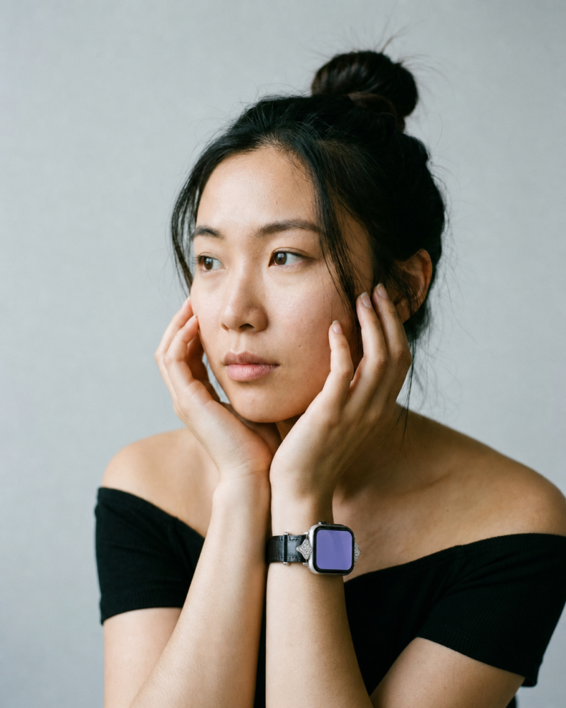 Woman wearing black leather strap smartwatch on wrist against neutral background